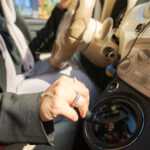 Cropped photo of female hand with rings on car gearbox