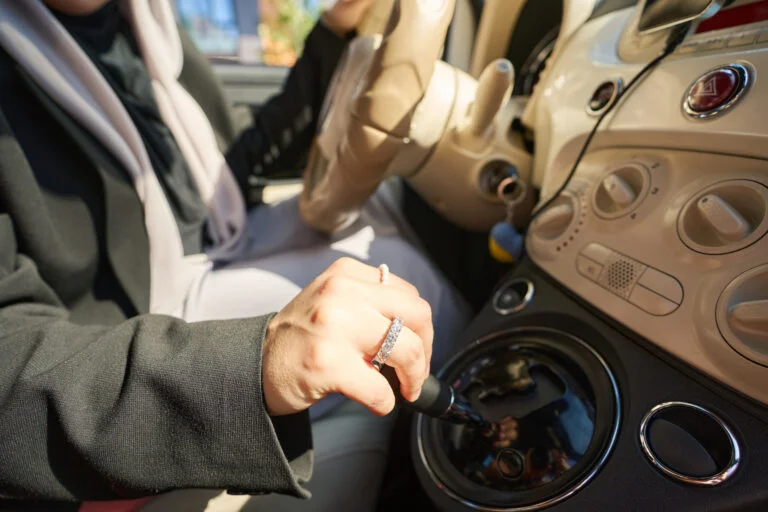 Cropped photo of female hand with rings on car gearbox