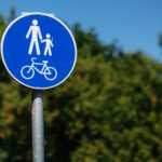 pedestrian bicycle zone in blue circle on background of green trees in park